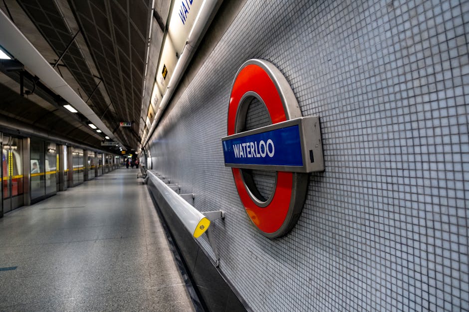 A white sign with blue and red roundel branding a London Underground station entrance at Ealing Broadway. The sign displays directional information for the District line and Elizabeth line, along with